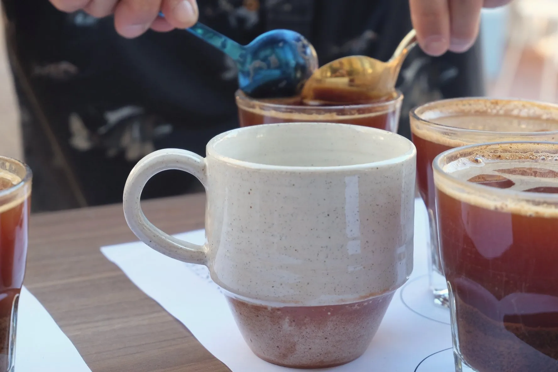 A cupping spoon lifting grounds from a glass