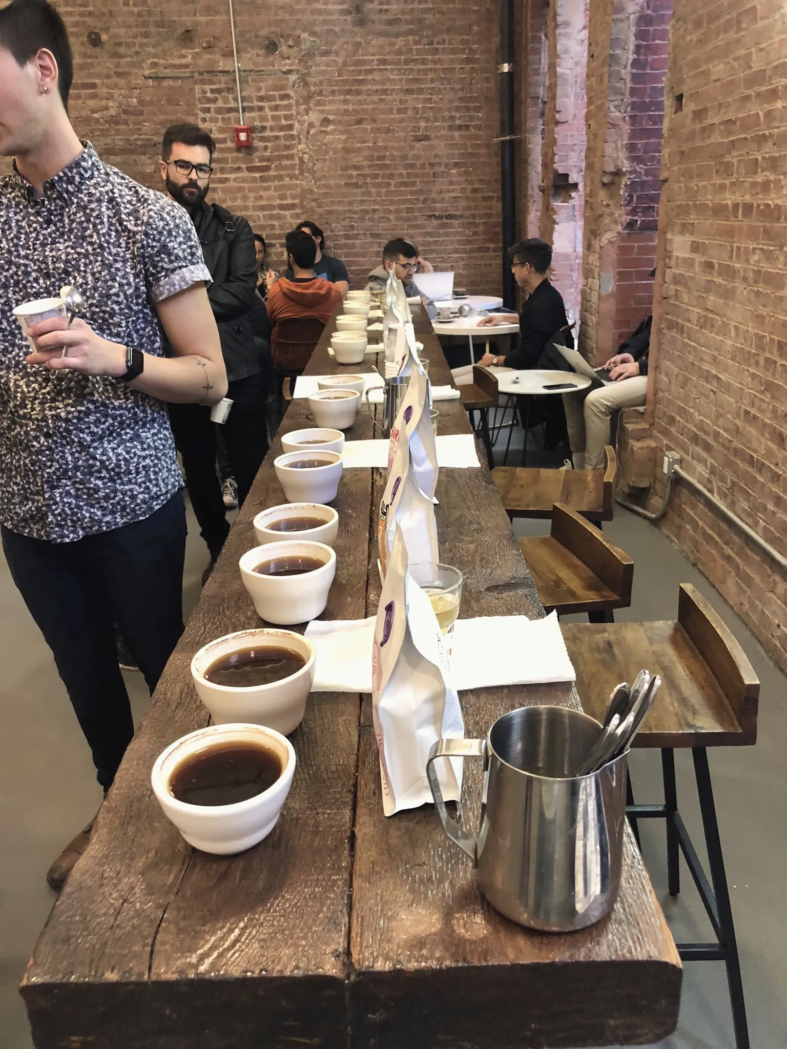 A long cupping table lined with rows of white coffee cups