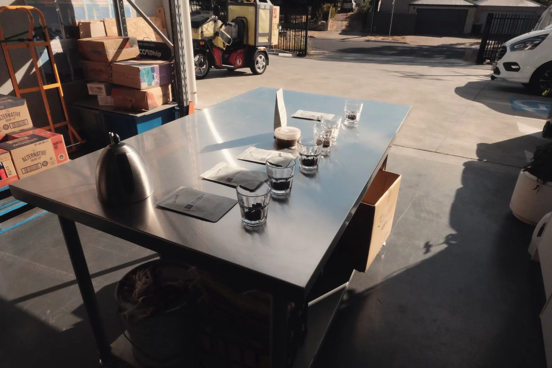 A long outdoor table set with rows of coffee cupping glasses